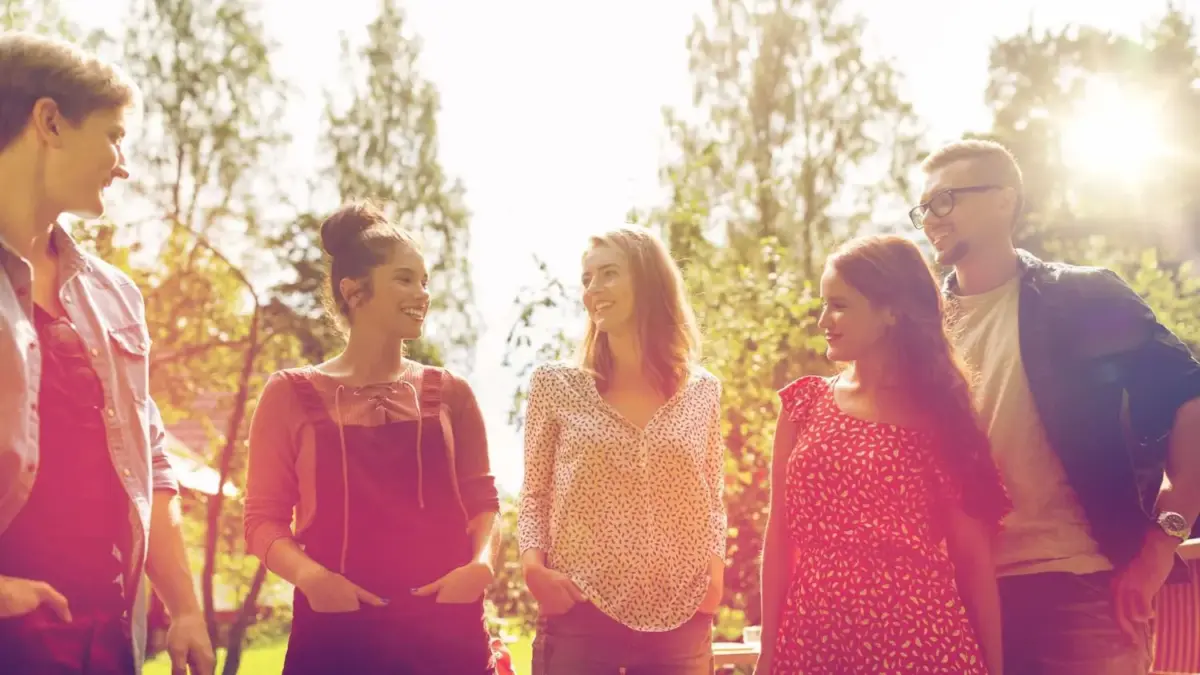 Group of friends talking and laughing in the park in summer