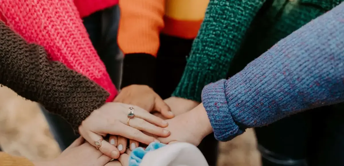 Close up view of people piling their hands on top of one another