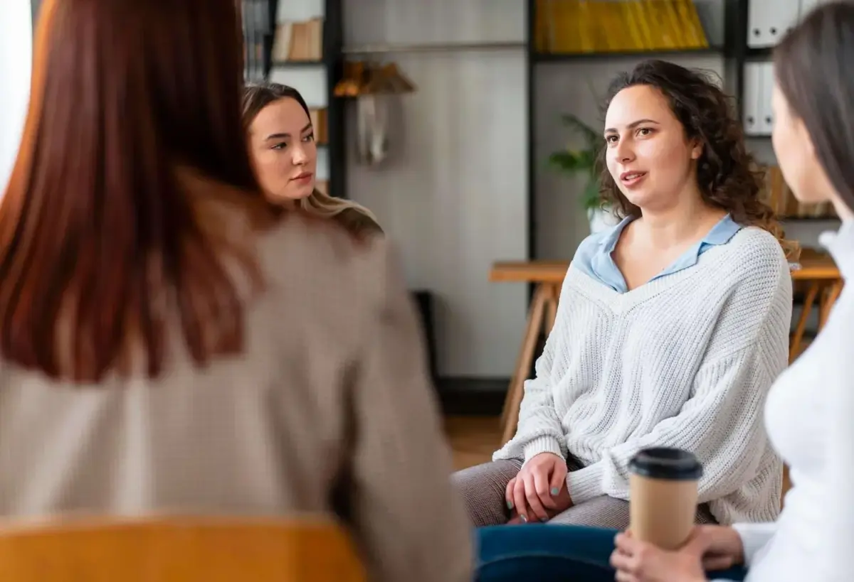 A group of women in an AA or Al-Anon group setting, talking
