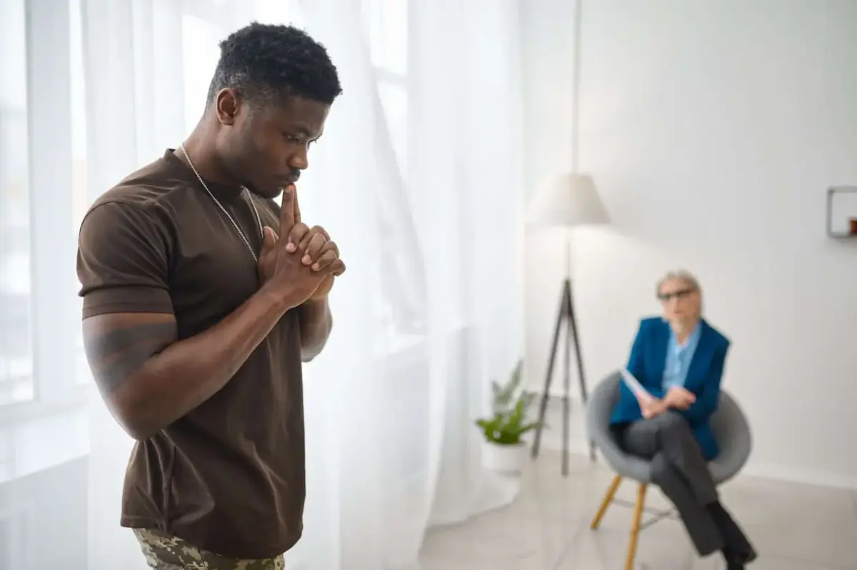 A man stands looking pensive as a therapist observes