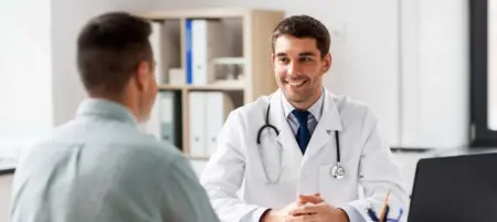 doctor with laptop and male patient discussing treatment