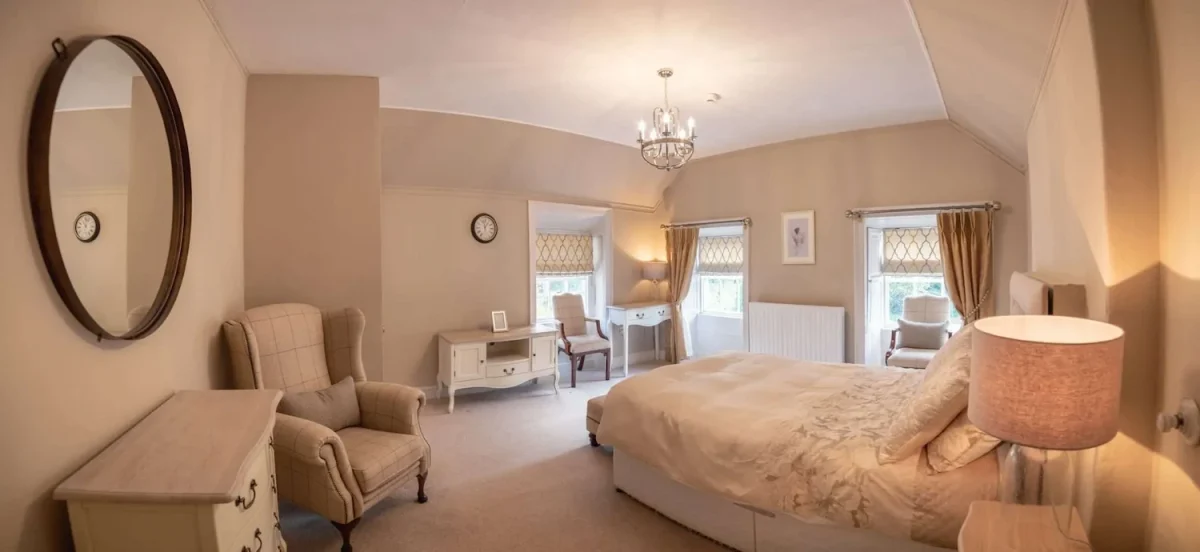 bedroom at Smarmore Castle rehab clinic showing double bed, armchairs, chest of drawers and writing desks