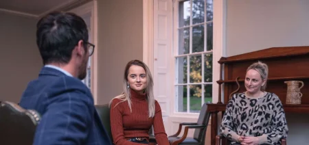 Three people sit in chairs inside talking at Smarmore Castle Private Rehab Clinic