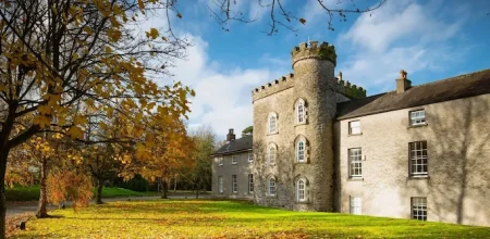 External photo of Smarmore Castle Drug and Alcohol Rehab Clinic in the sun with trees around in autumnal colours