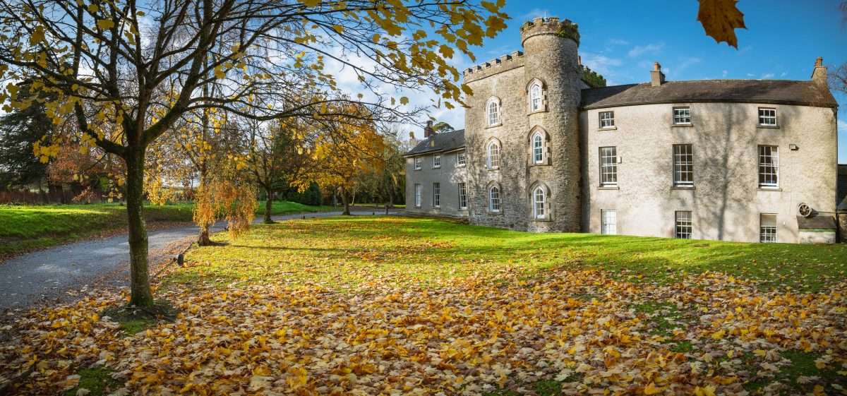 Smarmore Castle - a view from the side in autumn whith leaves on the ground depicting the place where you can access support for dual diagnosis during your addiction treatment.