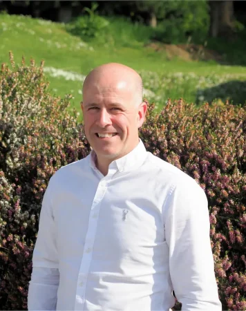 Portrait photo of David Gordon, addiction therapist at Smarmore Castle, photo taken outside with greenery and shrubs in the background