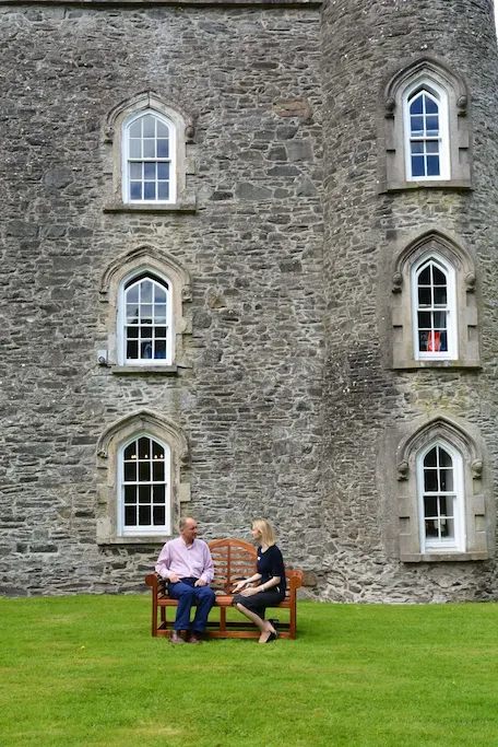 Two people sitting on a bench and talking outside of Smarmore Castle addiction treatment center in Ireland