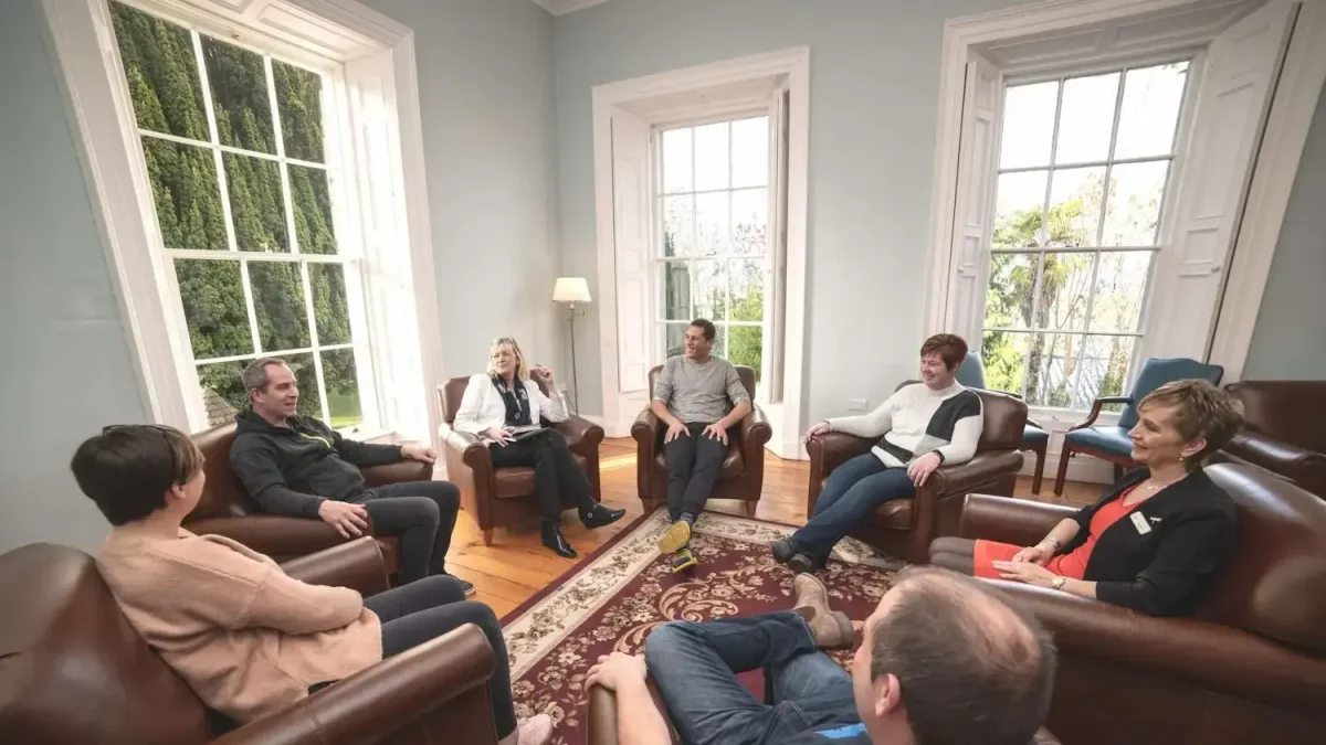 A group of people sitting in a circle during group therapy at Smarmore Castle Rehab in Ireland