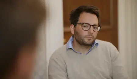 A man wearing a beige jumper talking to a therapist about heroin addiction.