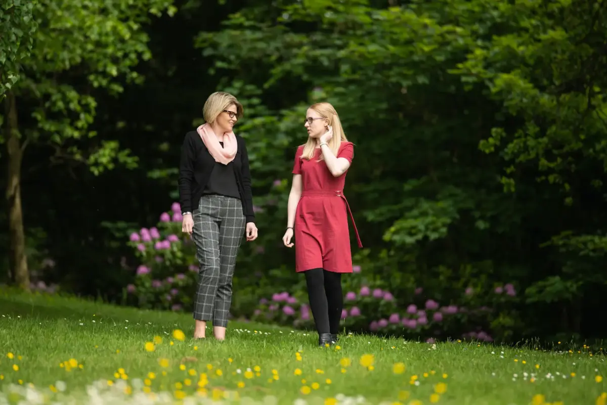 Two people walk and talk outside in beautiful gardens during addiction rehab